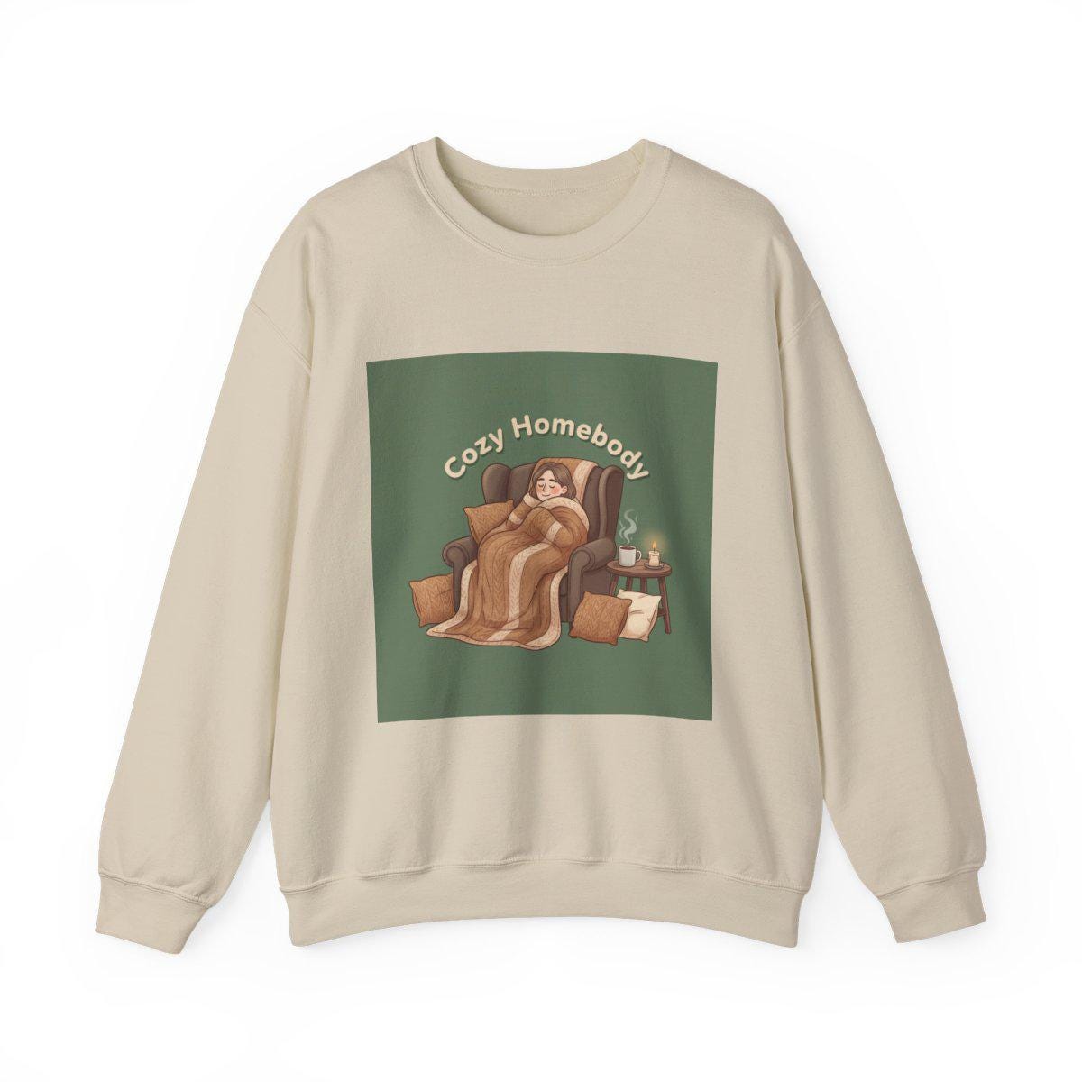 Beige sweatshirt with a graphic of a person in a blanket on a green background, labeled 'Cozy Homebody'.