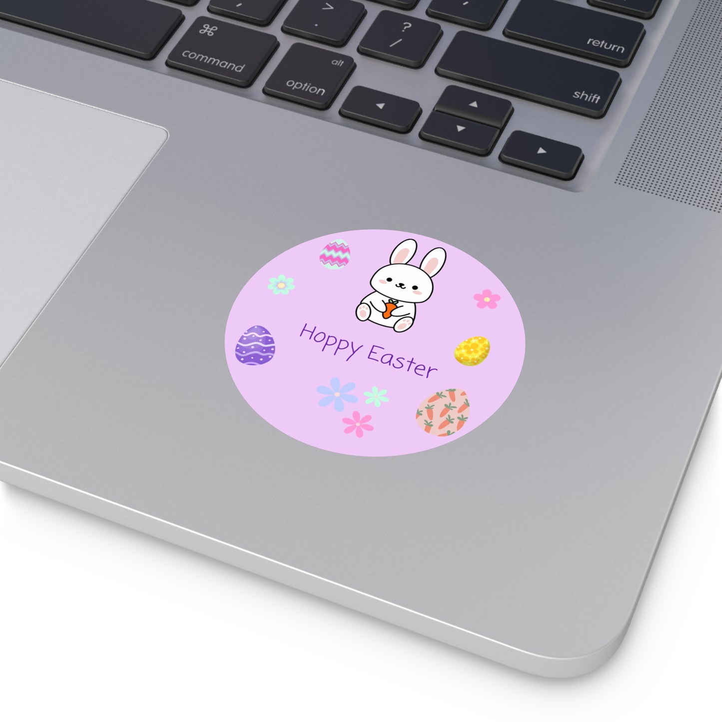 Laptop with a round Easter sticker featuring a bunny and eggs on a pink background.