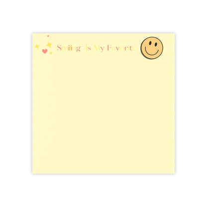 Yellow notepad with smiley face and text 'Smiling is my favorite' on a white background