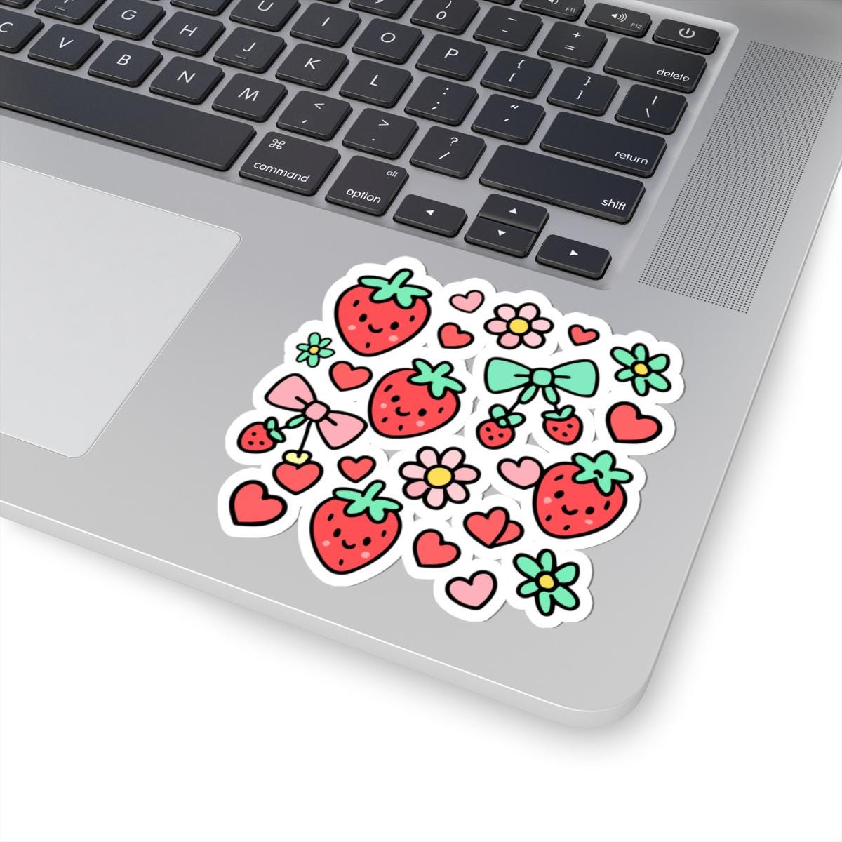 Laptop with a sticker featuring strawberries, flowers, and hearts on the palm rest area.