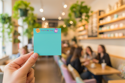 Hand holding sticky note with cafe backdrop